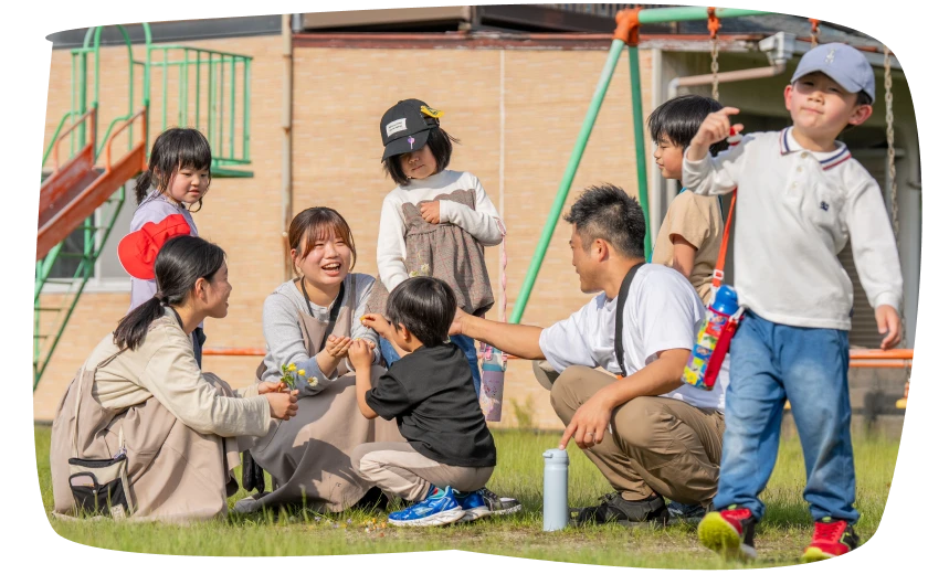 公園で輪になって遊ぶ子どもたちとスタッフ